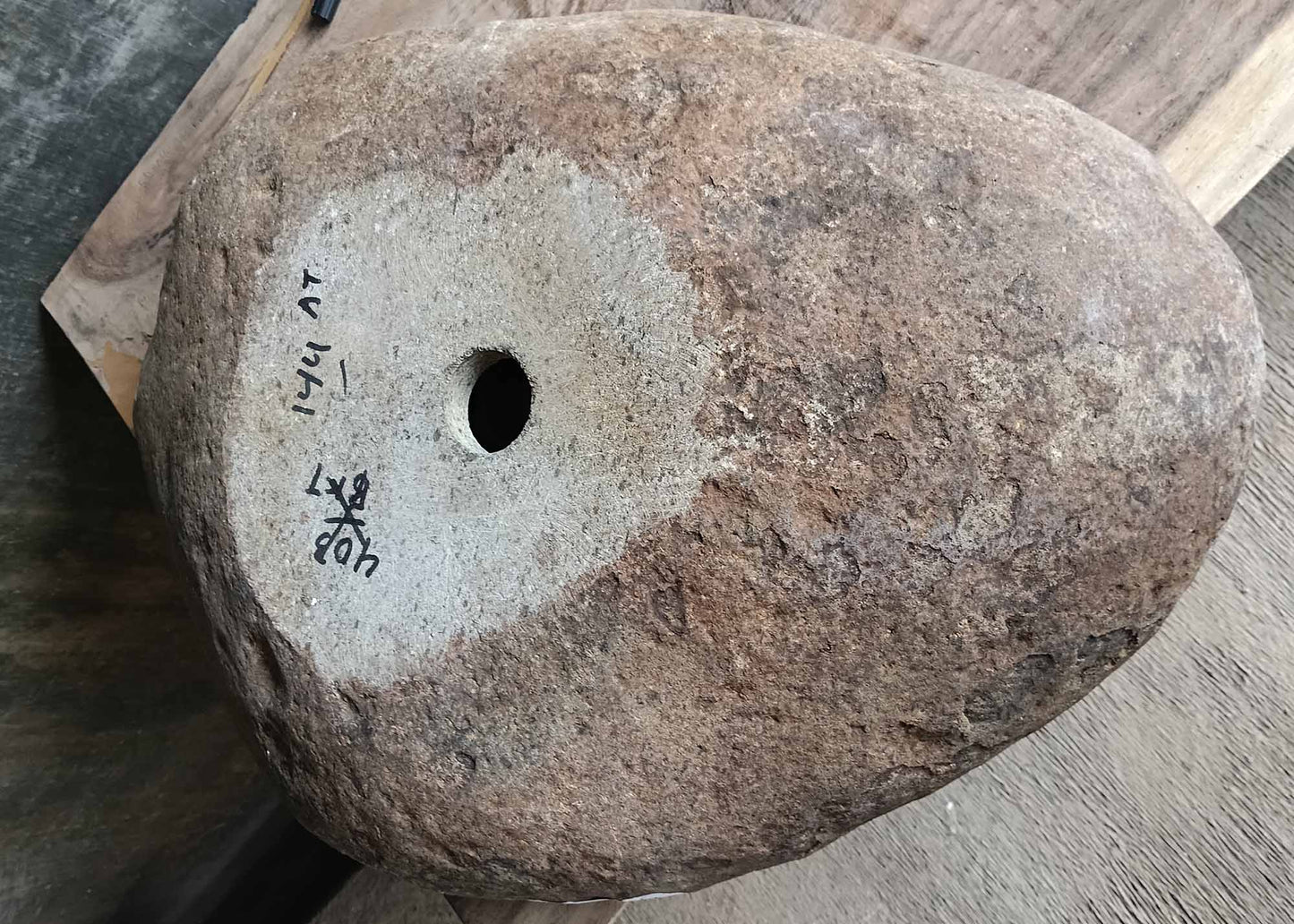 Bottom view of river stone sink with rough natural stone underside and visible product dimensions label