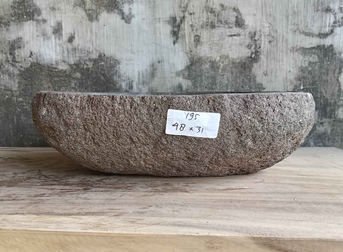 Back side of brown 18×12 inch stone sink showing raw textured surface and curved form