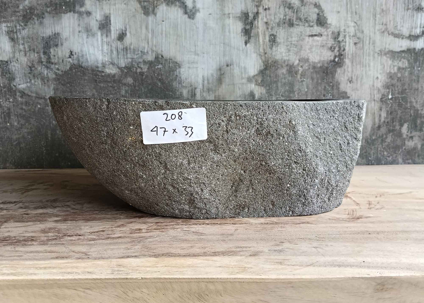 Back view of handcrafted gray river stone sink with raised rear section and curved form