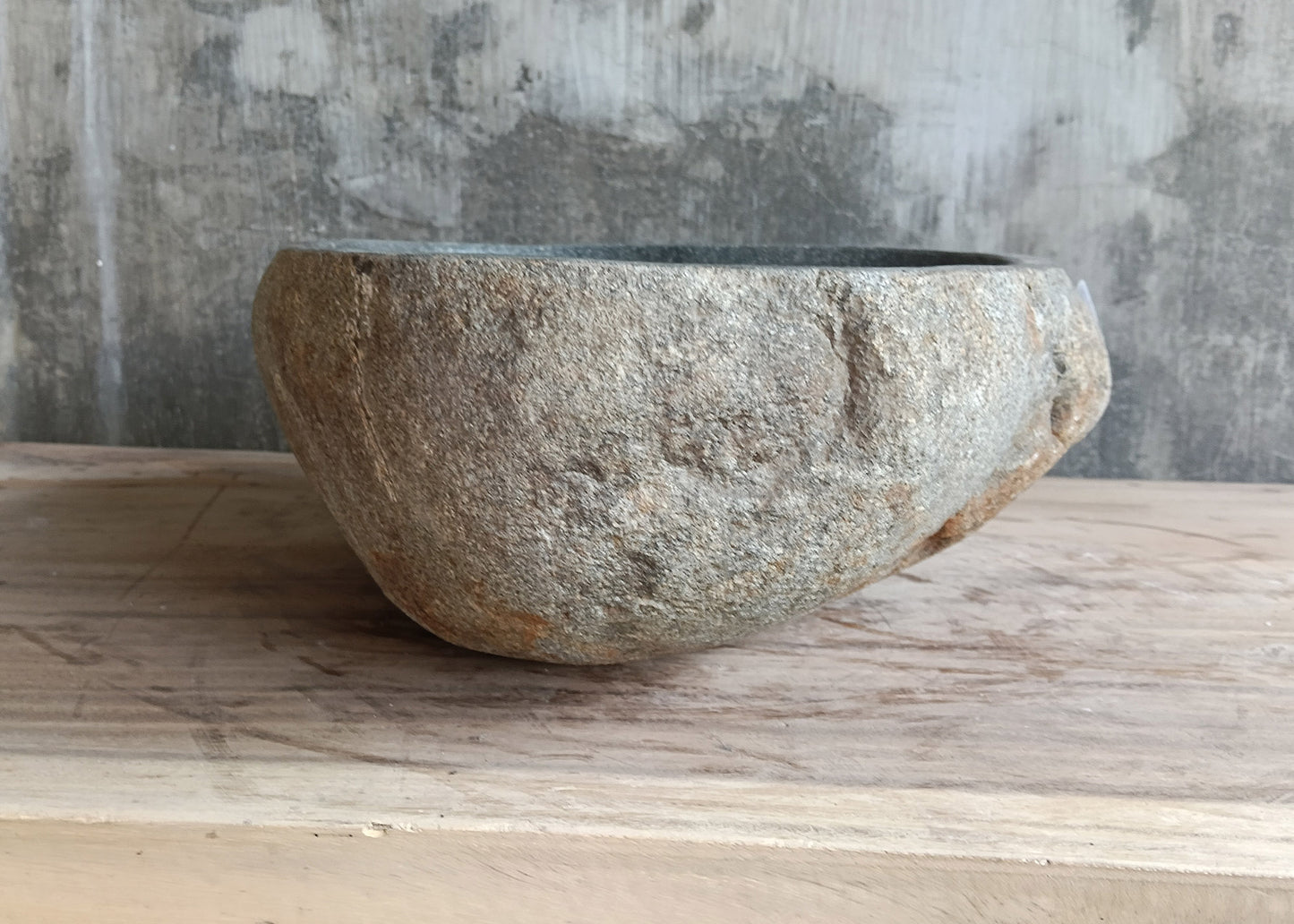 Hand-carved river stone sink with textured raw exterior and polished interior