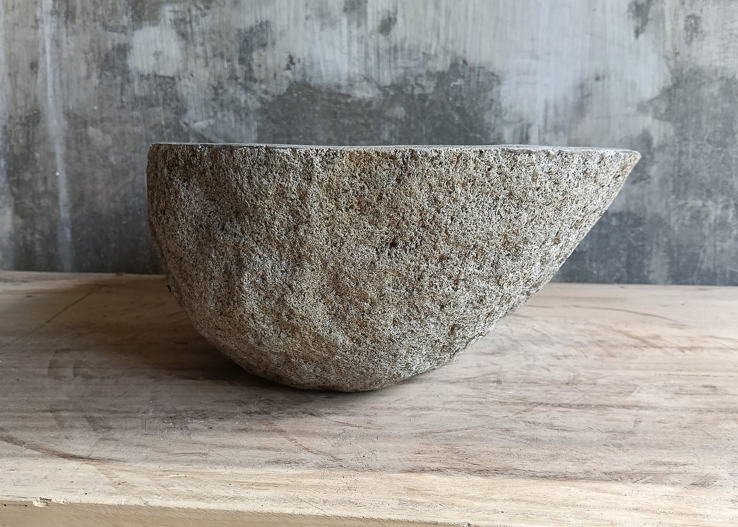 Left side of gray 17×12 inch river stone sink with tapered shape and porous surface