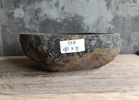 Front side of handcrafted dark gray stone sink showing curved oval profile and natural texture