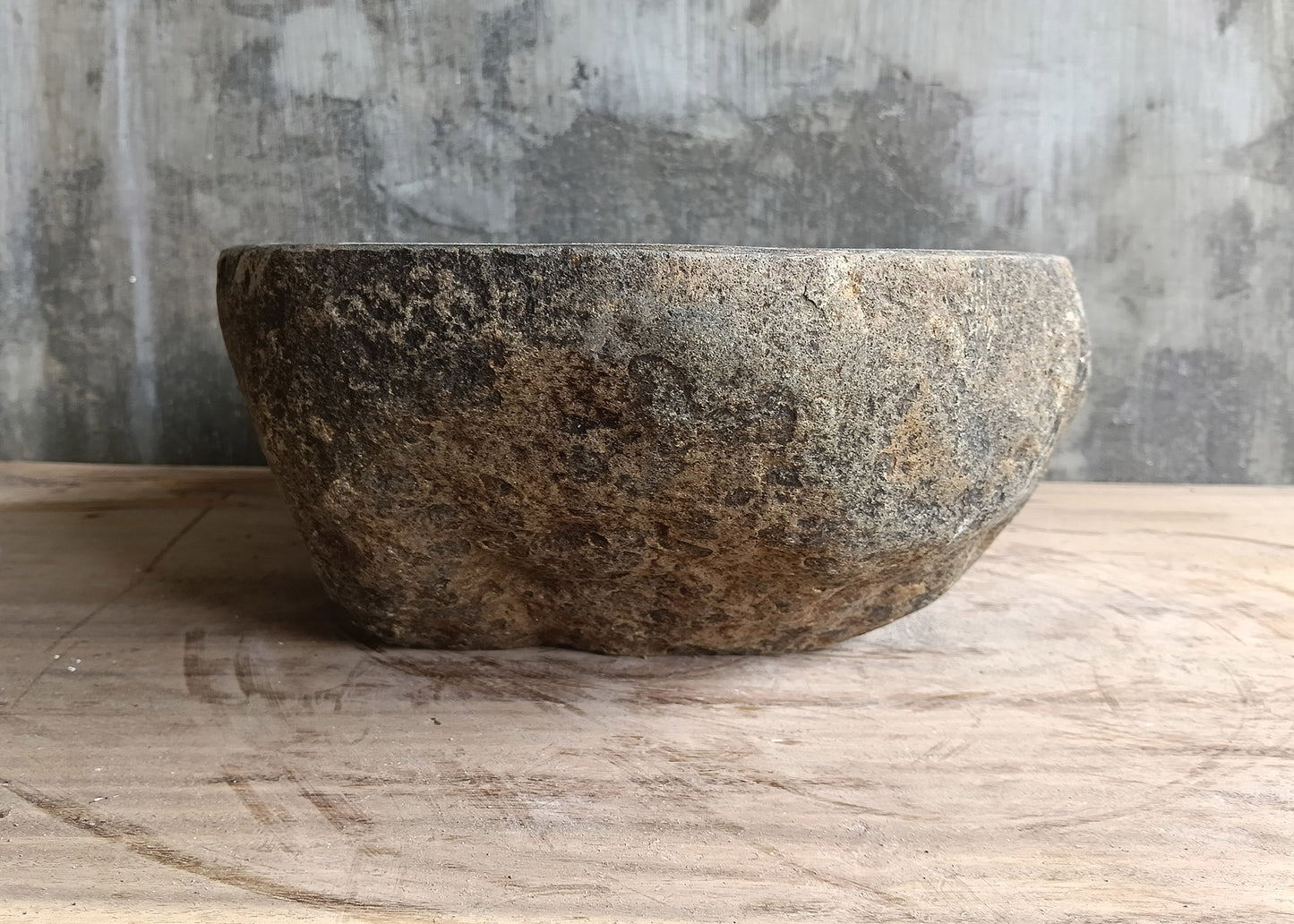 Left side of dark gray river sink with elegant oval silhouette and natural finish