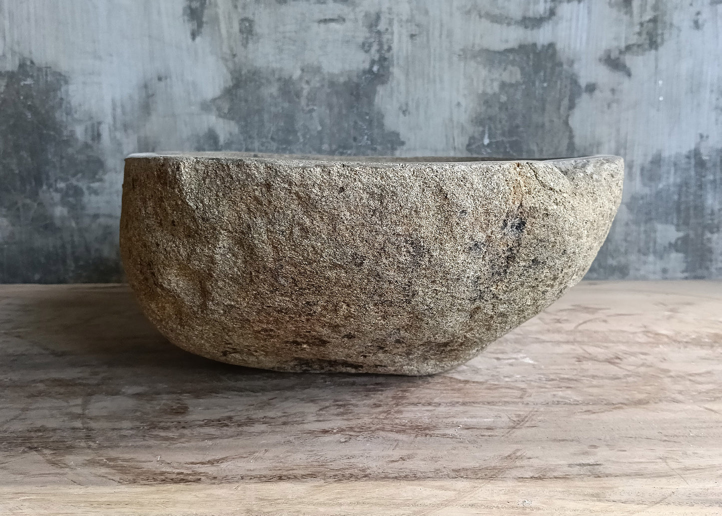 Left side of oval river stone sink with boat-like profile and detailed exterior