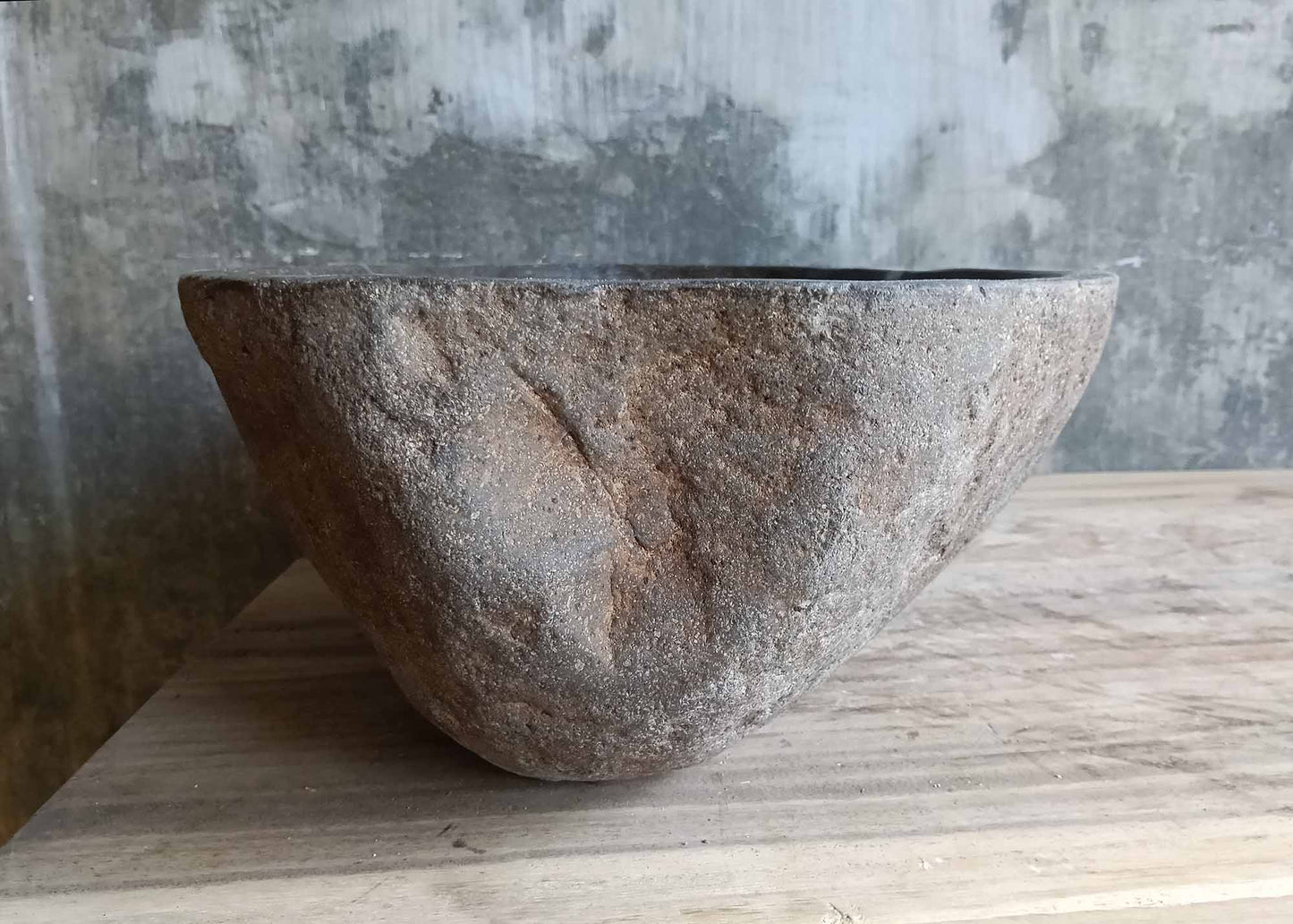 Right side of dark gray narrow stone sink with rugged exterior