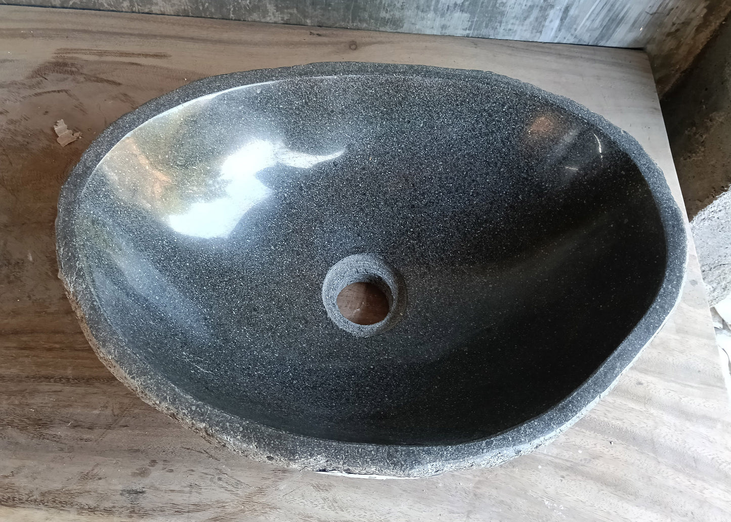 Top view of handcrafted river stone sink with dark polished interior and organic shape