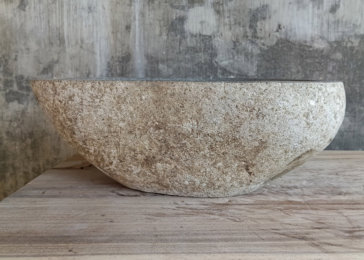 Back view of light gray stone sink with unique pear-shaped design and textured exterior