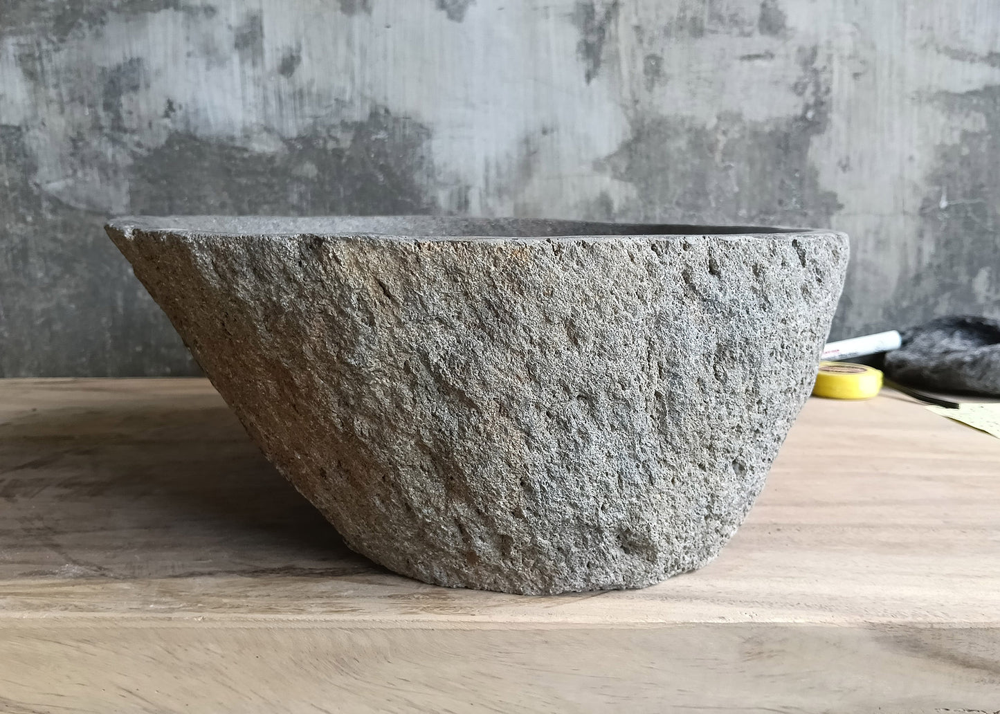 Left side of boat-shaped gray stone sink with rounded oval form