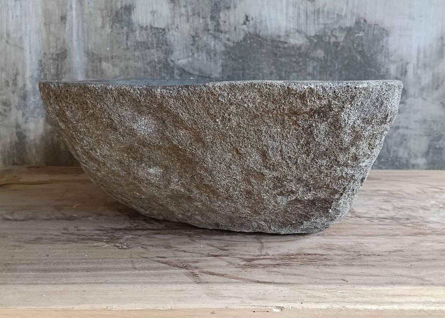 Angled side of rustic river stone basin with natural lines