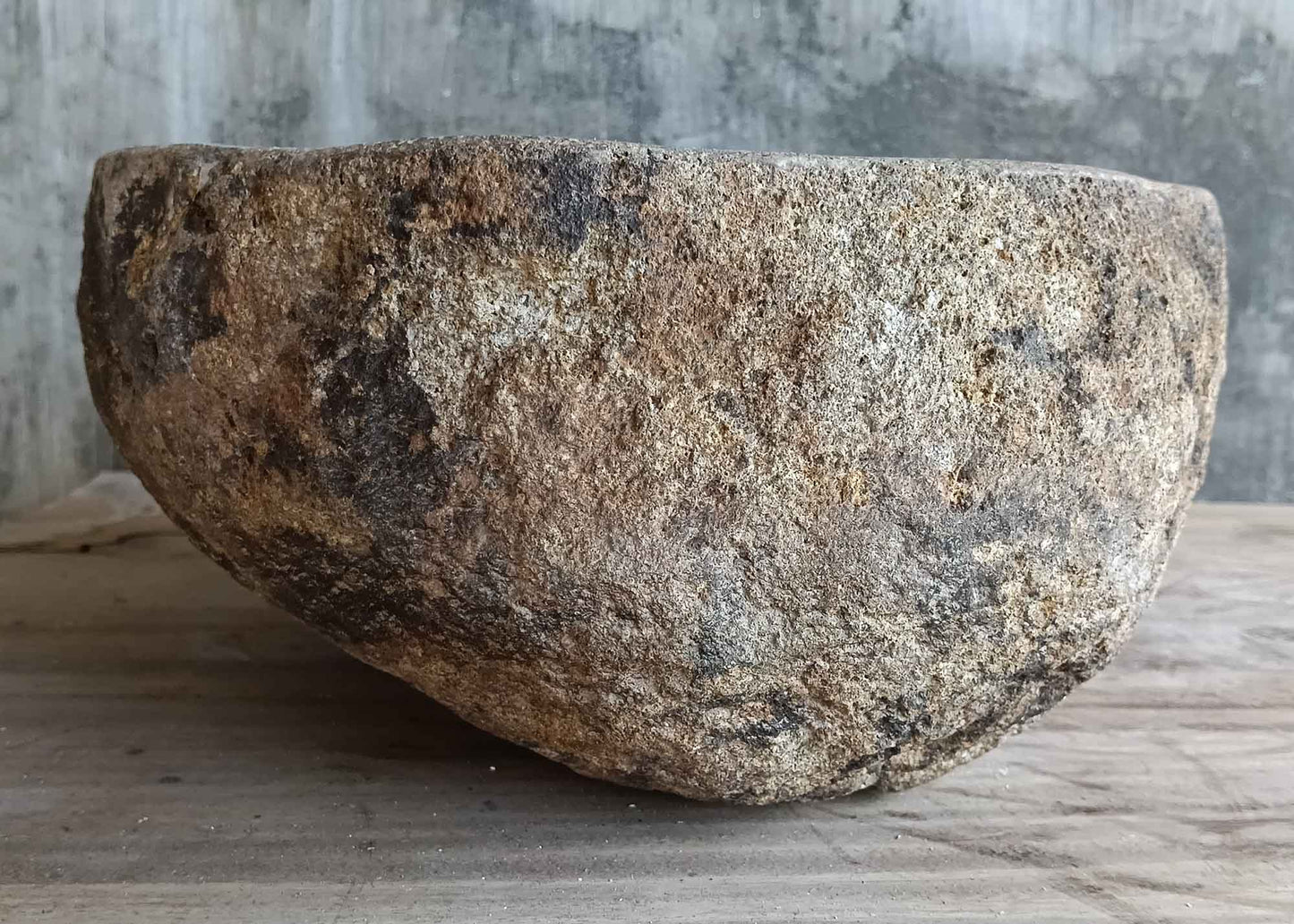 Left side view of handcrafted light beige river stone sink highlighting outer stone texture