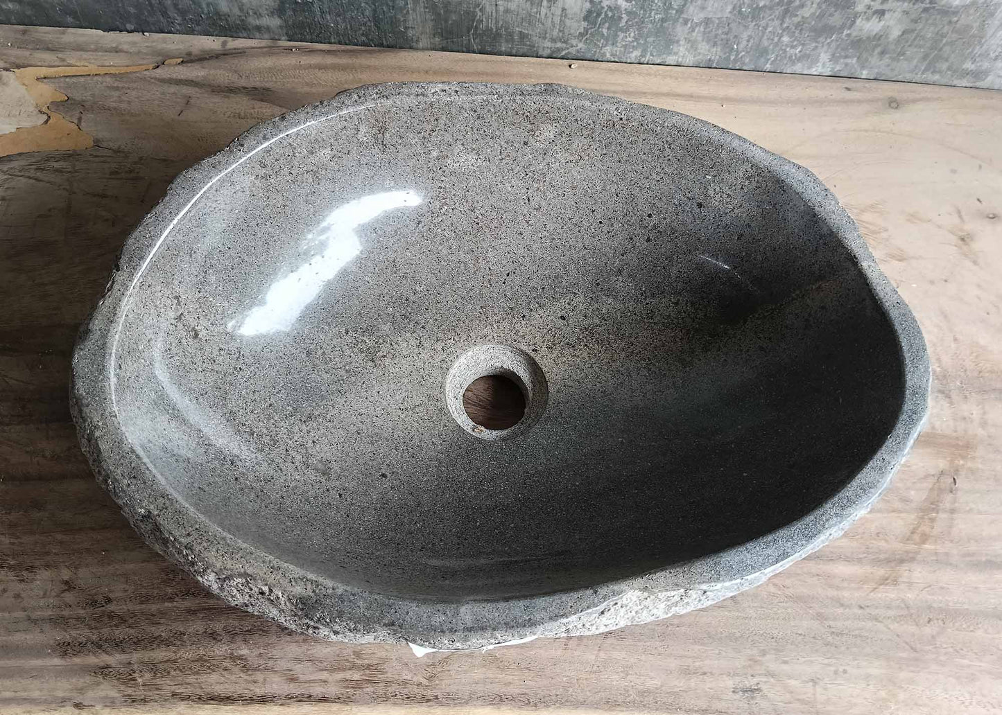Top view of a handcrafted river stone sink with smooth grey polished interior and natural edges
