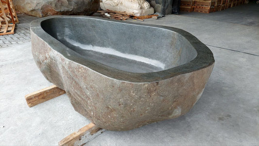 Side view of natural river stone bathtub showing rugged exterior