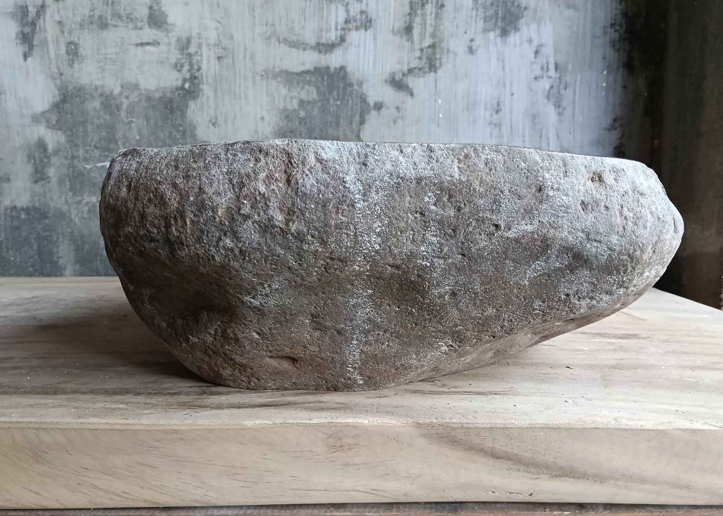 Left side view of gray handcrafted river stone sink with uneven organic contours
