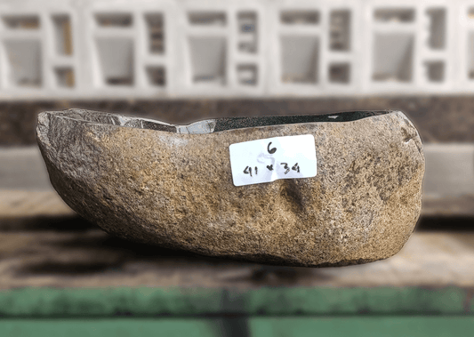 Side view of river stone sink 6006-4134 on wood slab showing handcrafted shape and finish