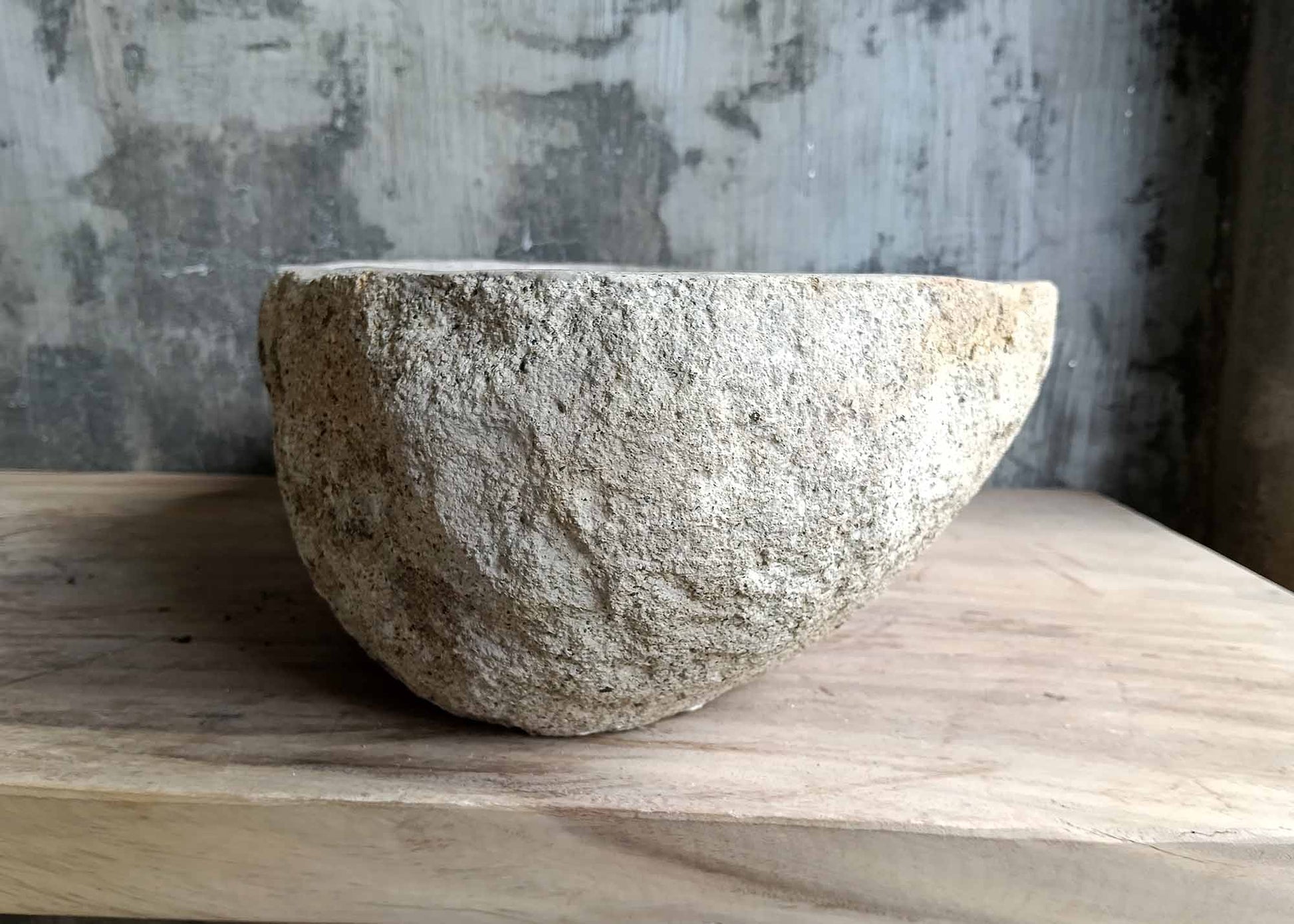 Right side view of oval beige river stone sink SKU 6026-5435 with rough textured exterior and smooth interior finish
