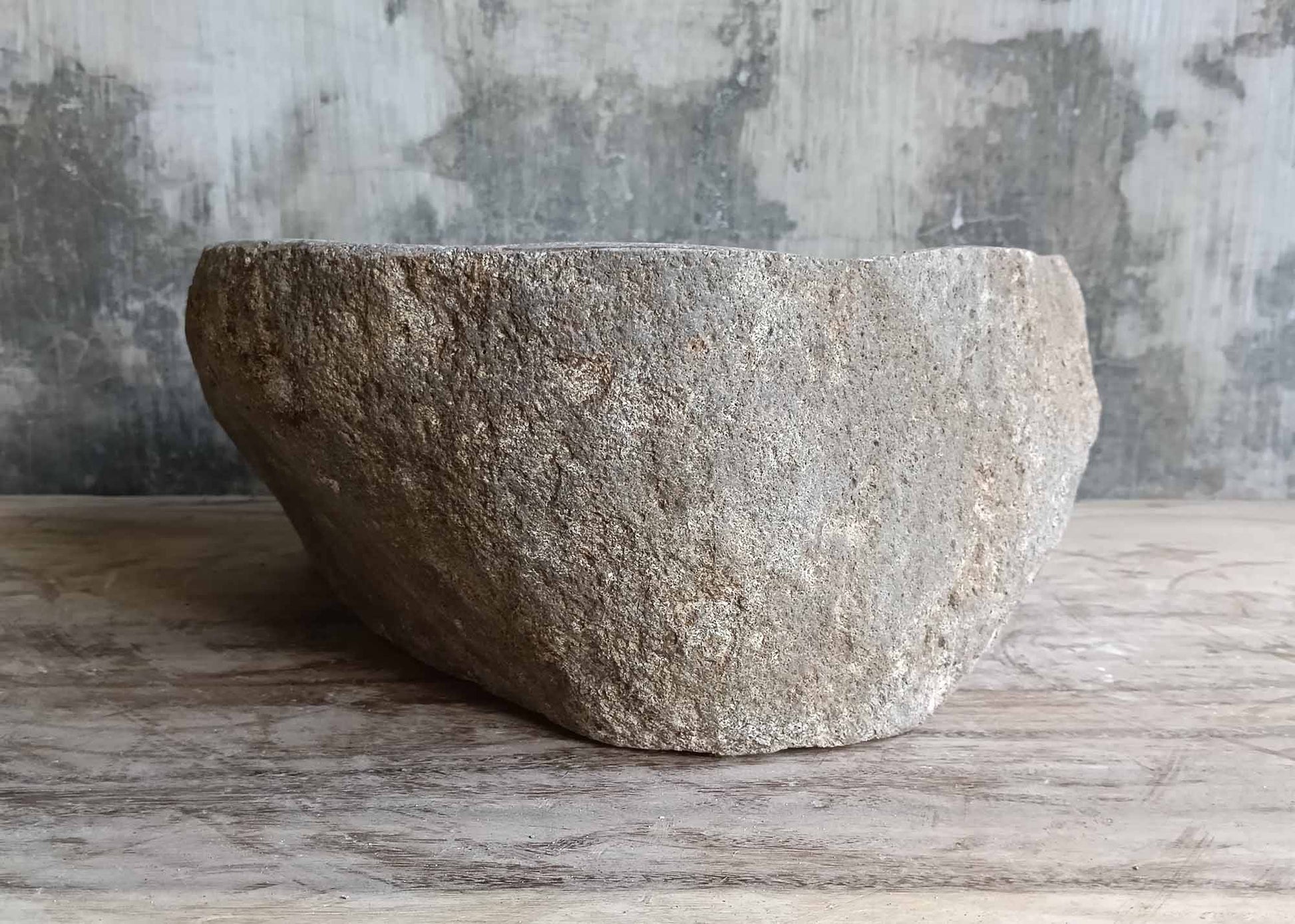 Right view of triangular stone sink with smooth interior and rough exterior
