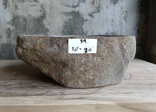 Front view of rustic gray stone sink with organic triangular shape
