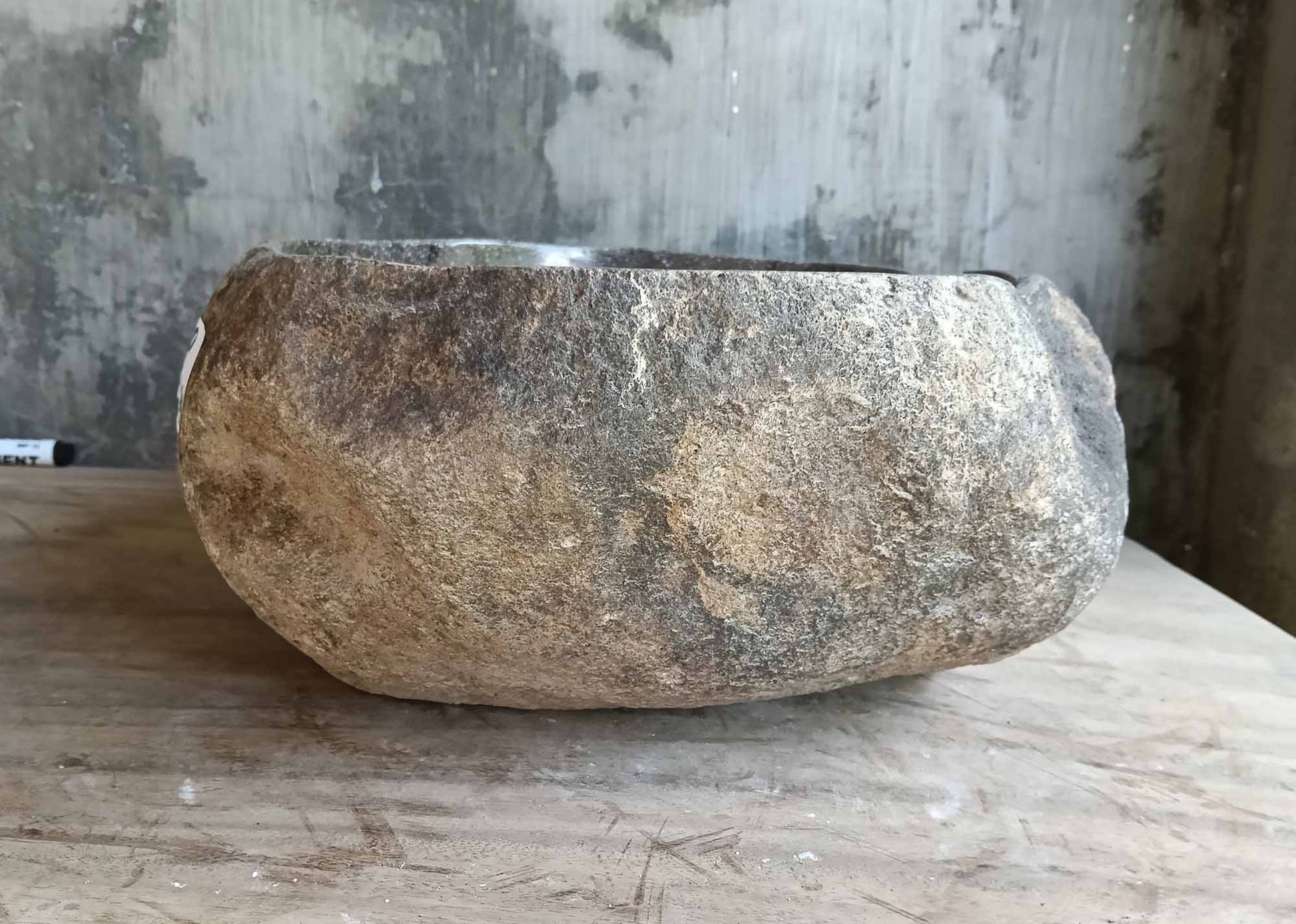 Back angle of handcrafted stone basin with textured brown-gray shell
