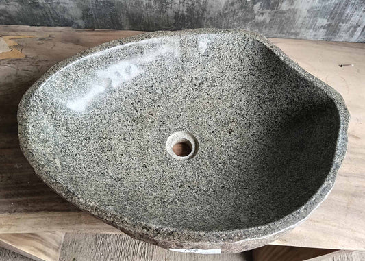Top view of handcrafted river stone sink with natural polished granite surface and organic edges

