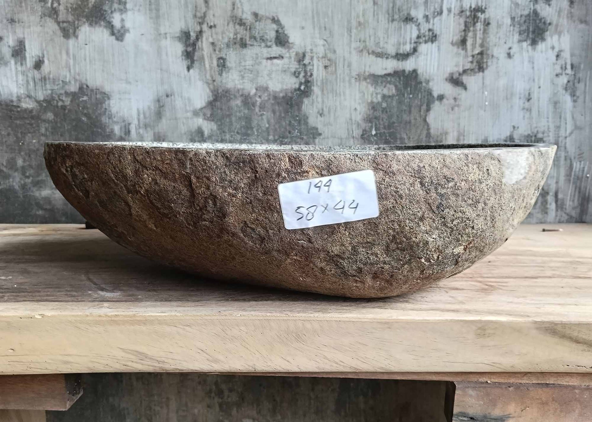 Front view of handcrafted river stone sink showing rough natural stone exterior and smooth polished interior
