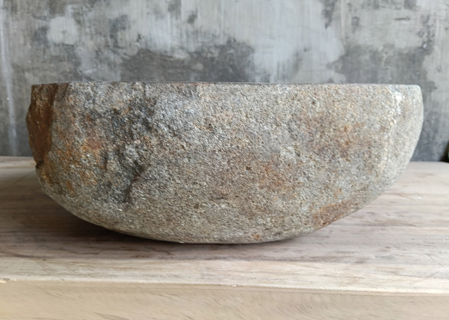 Gray stone bathroom sink with asymmetrical triangular shape on wooden surface
