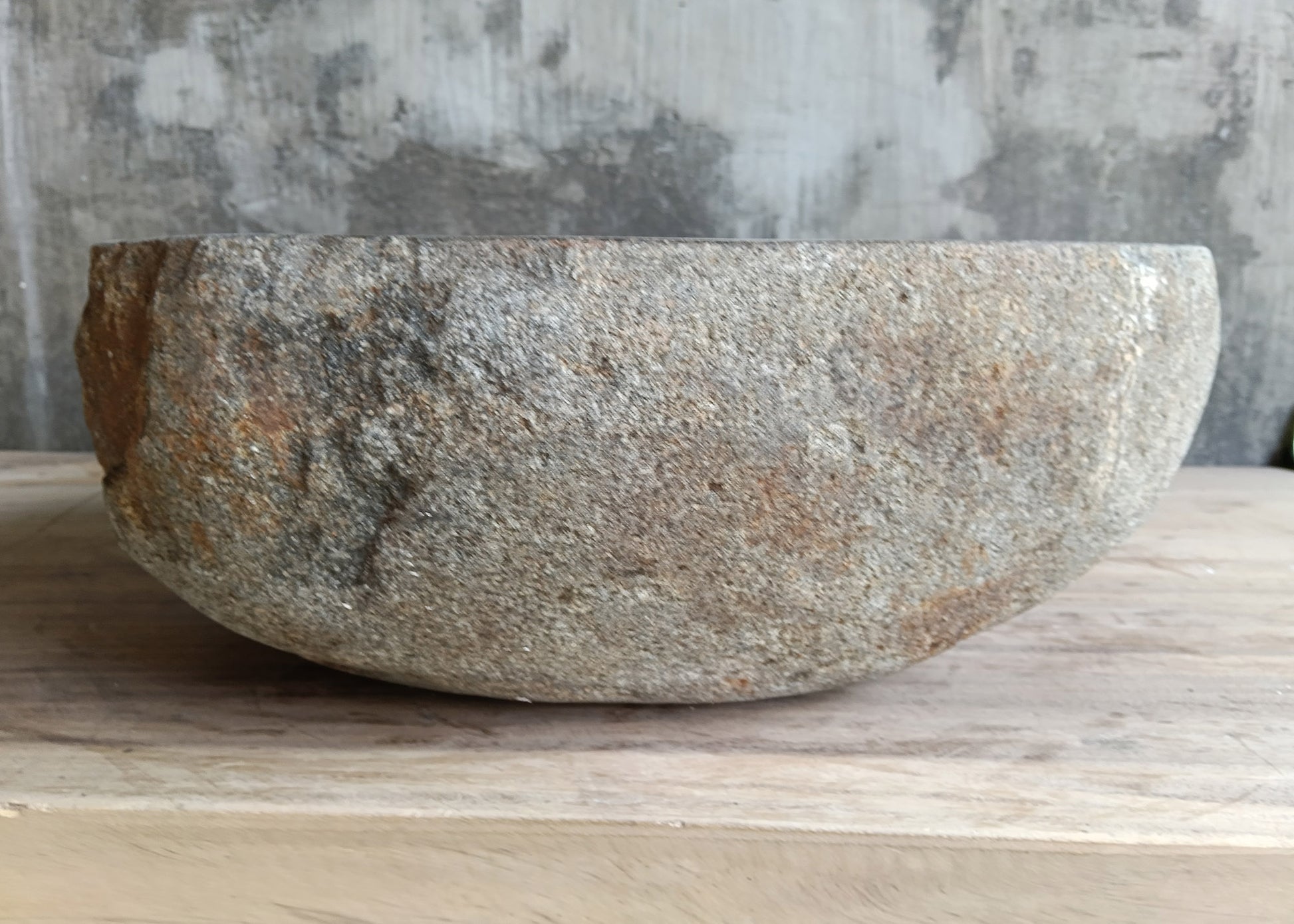 Gray stone bathroom sink with asymmetrical triangular shape on wooden surface
