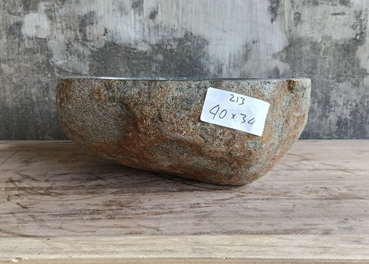 Side angle showing rough exterior of natural stone vessel sink in sculptural form
