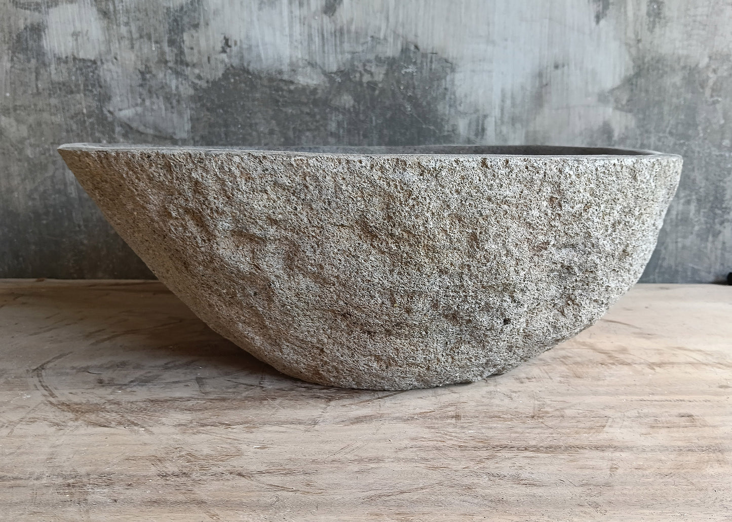 Back view of elongated 17×12 inch gray stone sink with raw exterior and curved form
