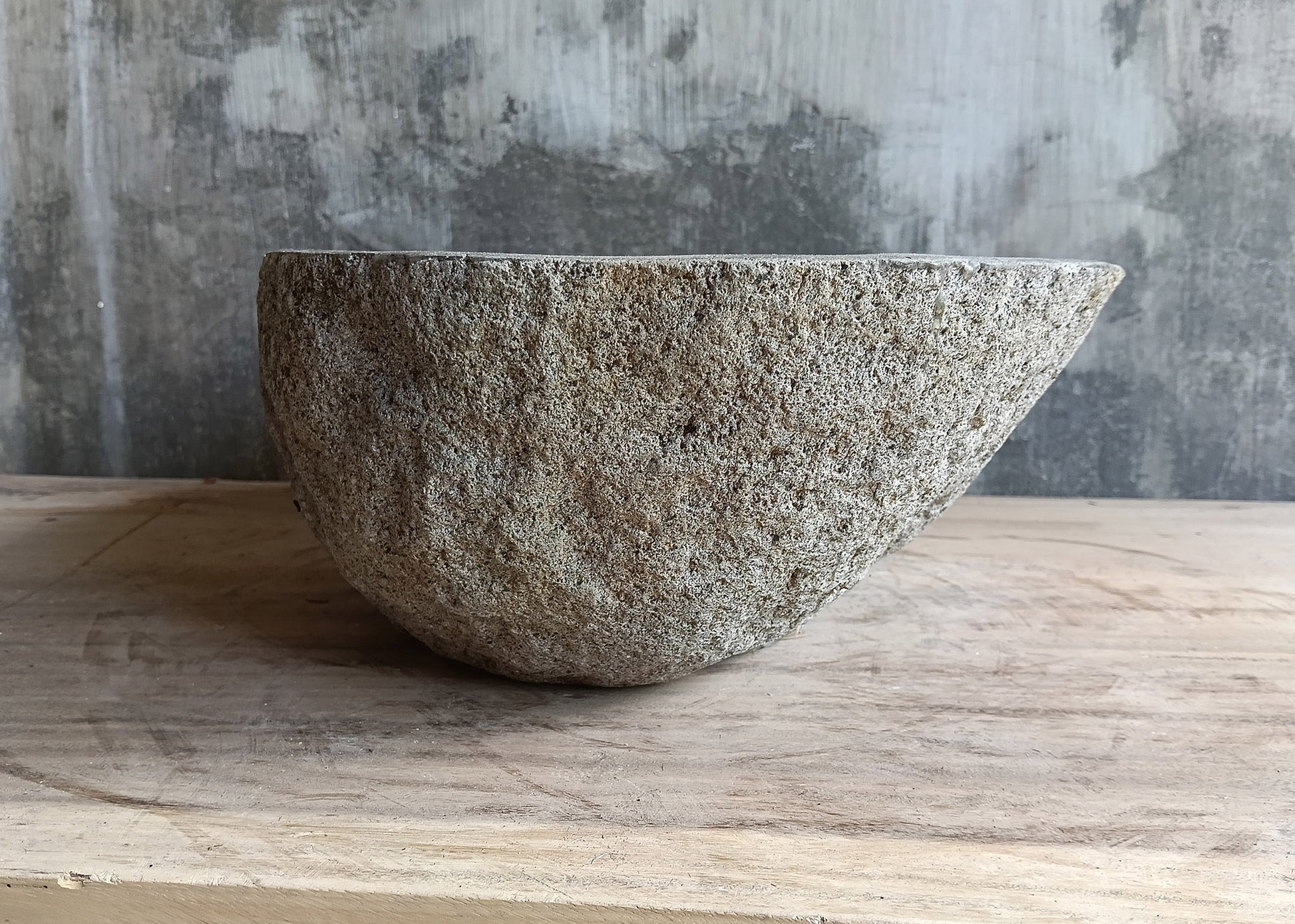 Left side of gray 17×12 inch river stone sink with tapered shape and porous surface
