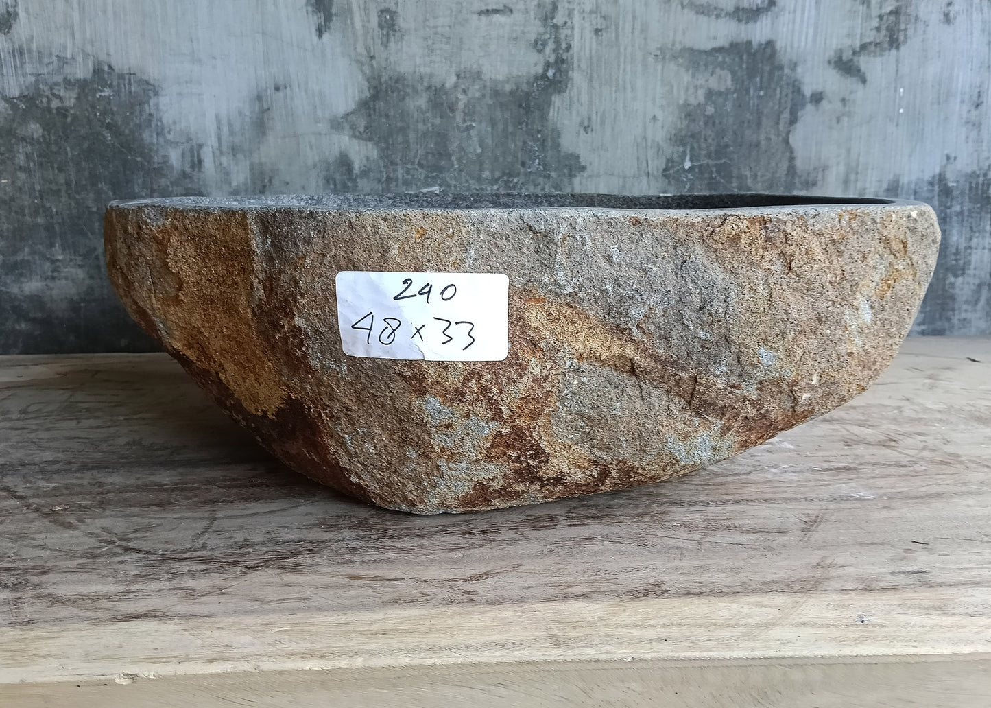 Front view of asymmetrical gray stone sink showing curved natural edges
