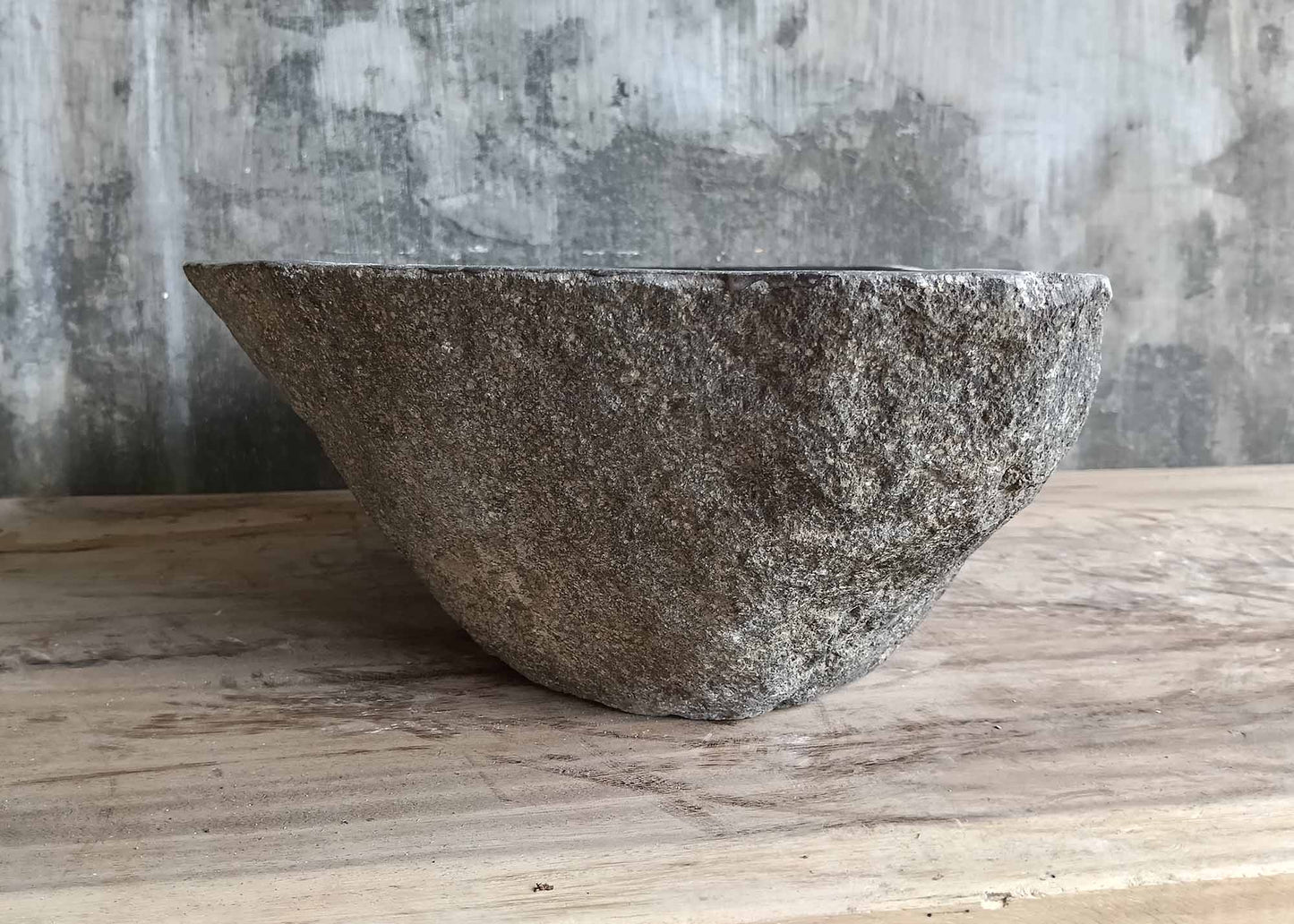 Left side of gray stone sink showing natural texture and angled shape
