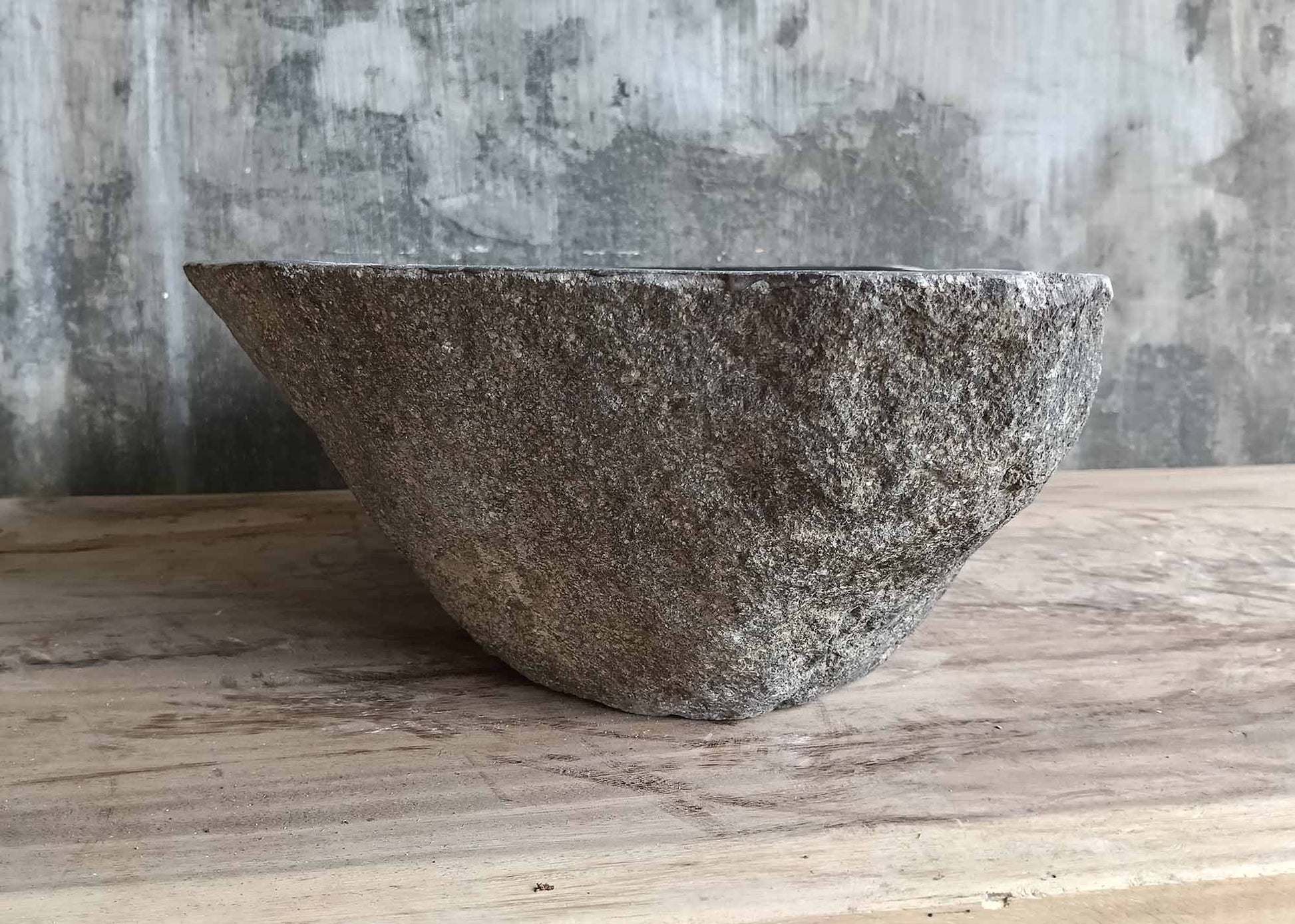 Left side of gray stone sink showing natural texture and angled shape
