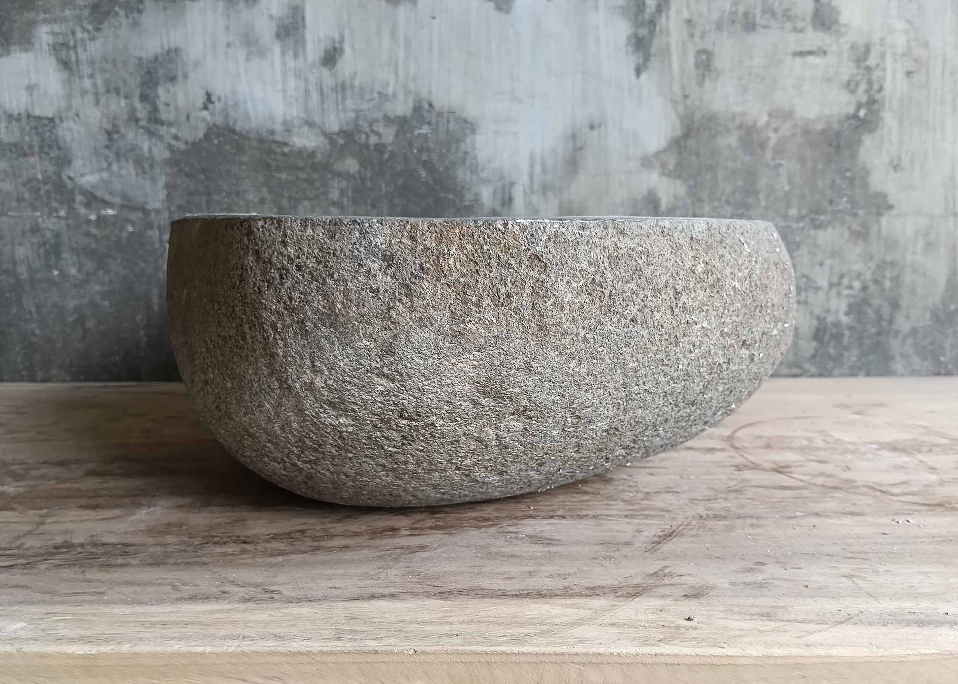 Left side of oval stone sink with asymmetrical form and gray color
