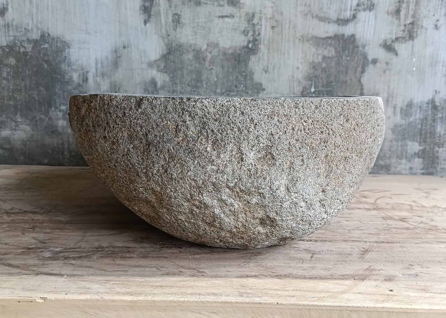Right profile of gray river stone sink with rounded triangle shape
