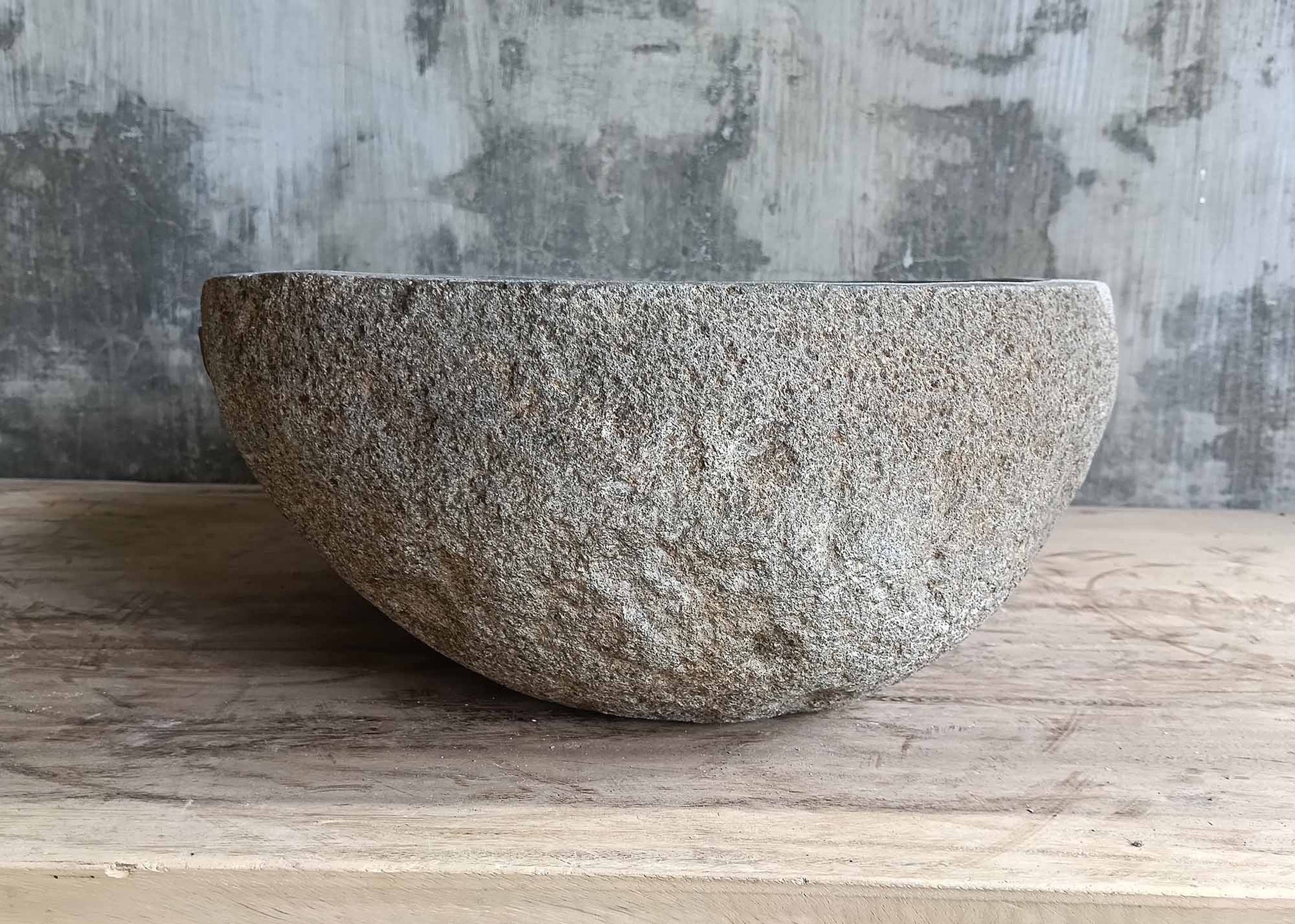 Right profile of gray river stone sink with rounded triangle shape
