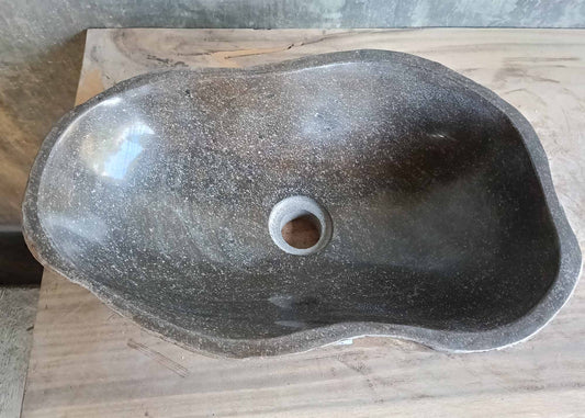 Top view of dark gray elongated stone sink with polished bowl
