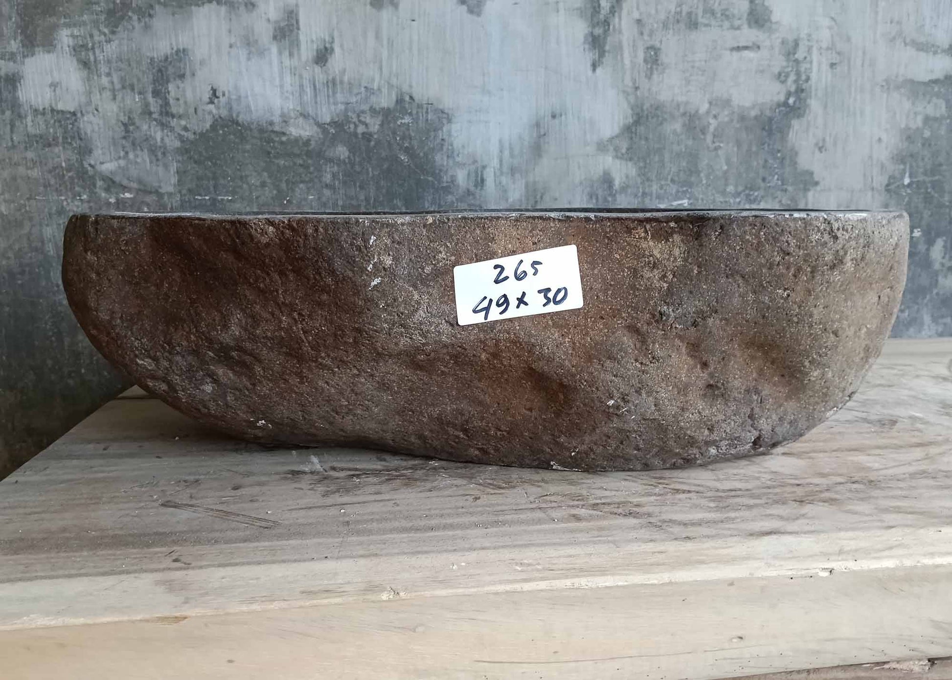 Front of handcrafted narrow river stone sink with raw edge

