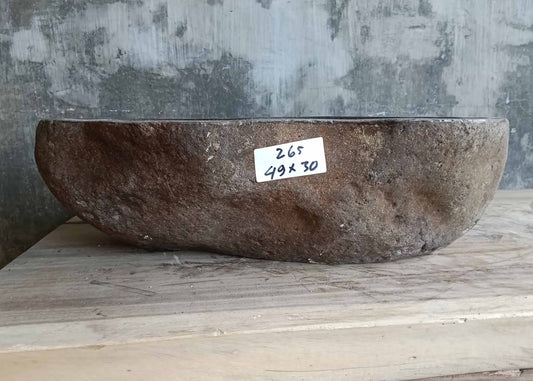 Front of handcrafted narrow river stone sink with raw edge
