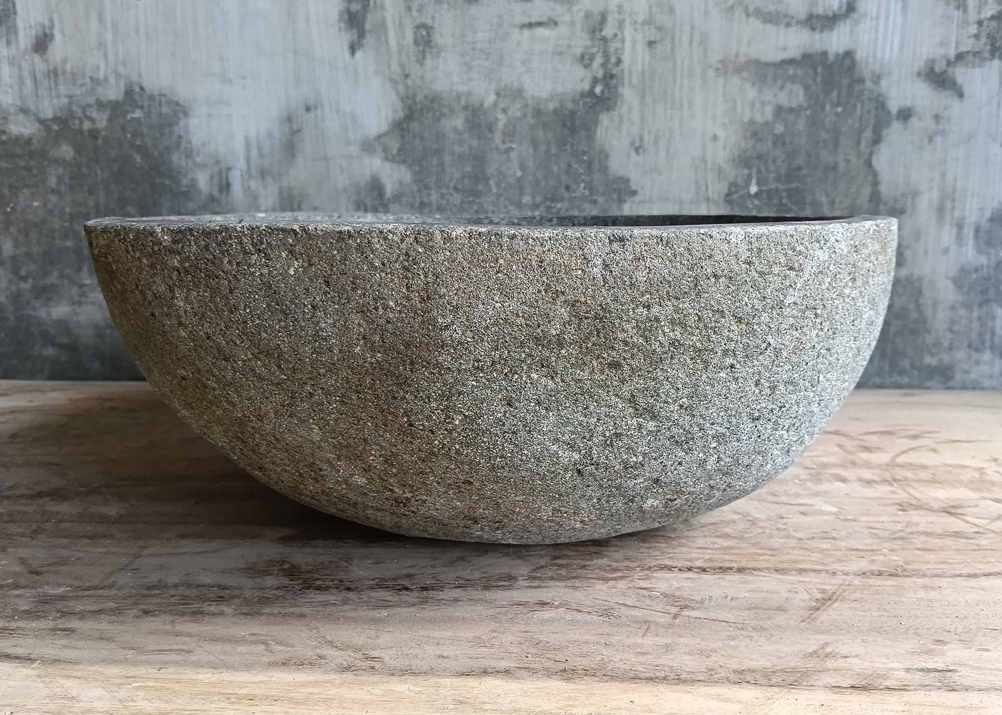 Right side of oval handcrafted sink made from gray stone
