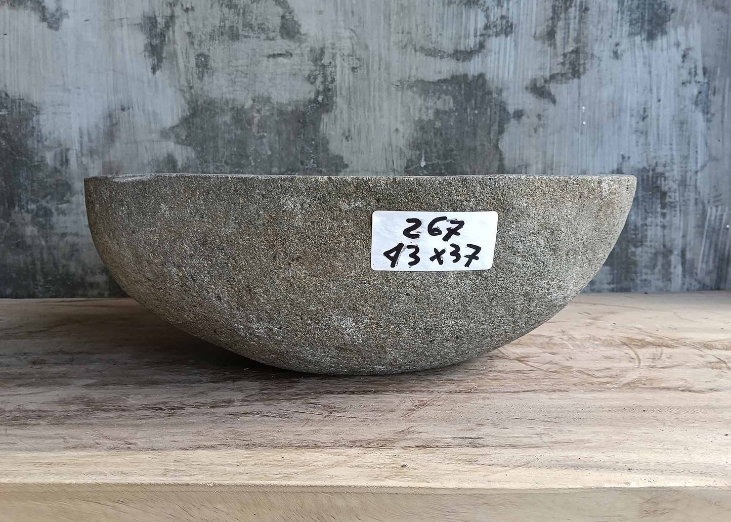Rear view of oval gray stone sink with natural outer texture
