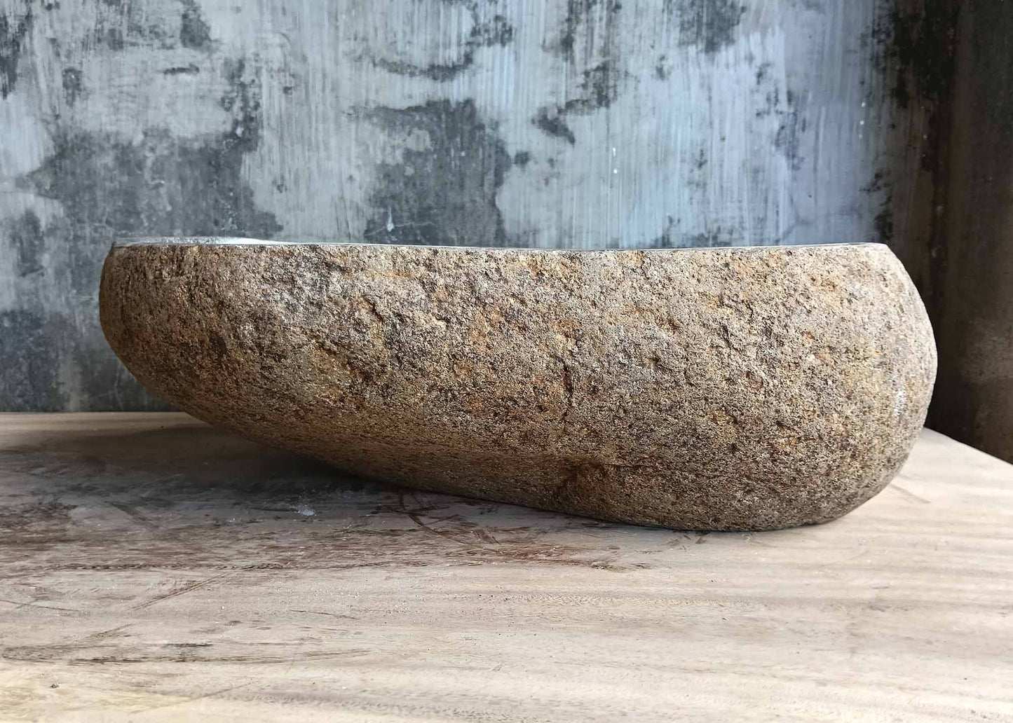 Back of four-sided gray river stone sink with rough outer texture
