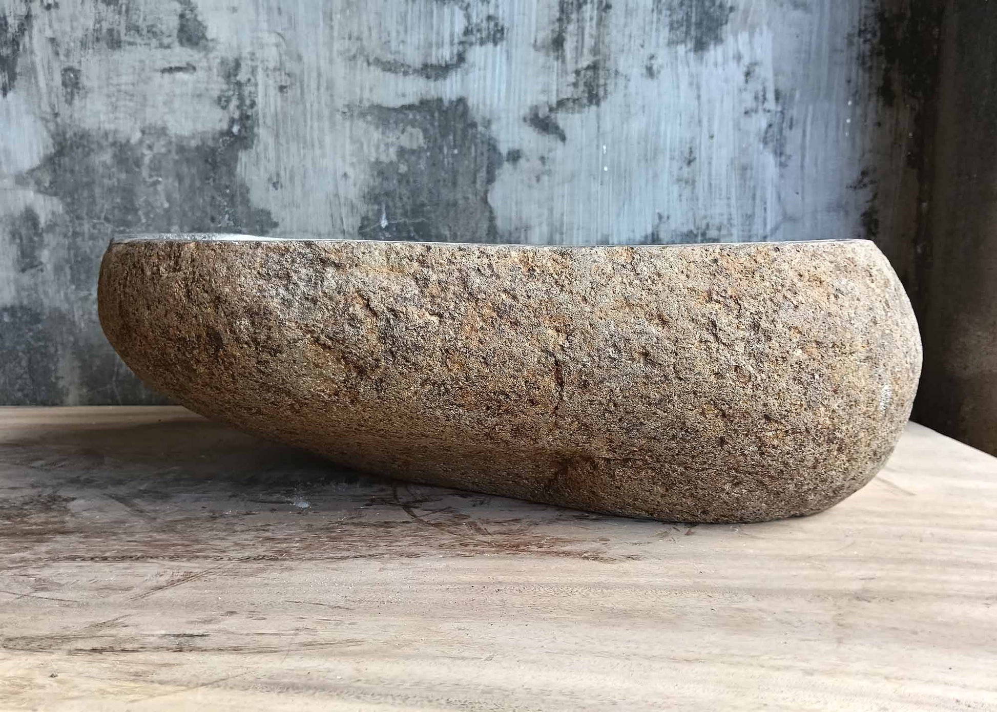 Back of four-sided gray river stone sink with rough outer texture
