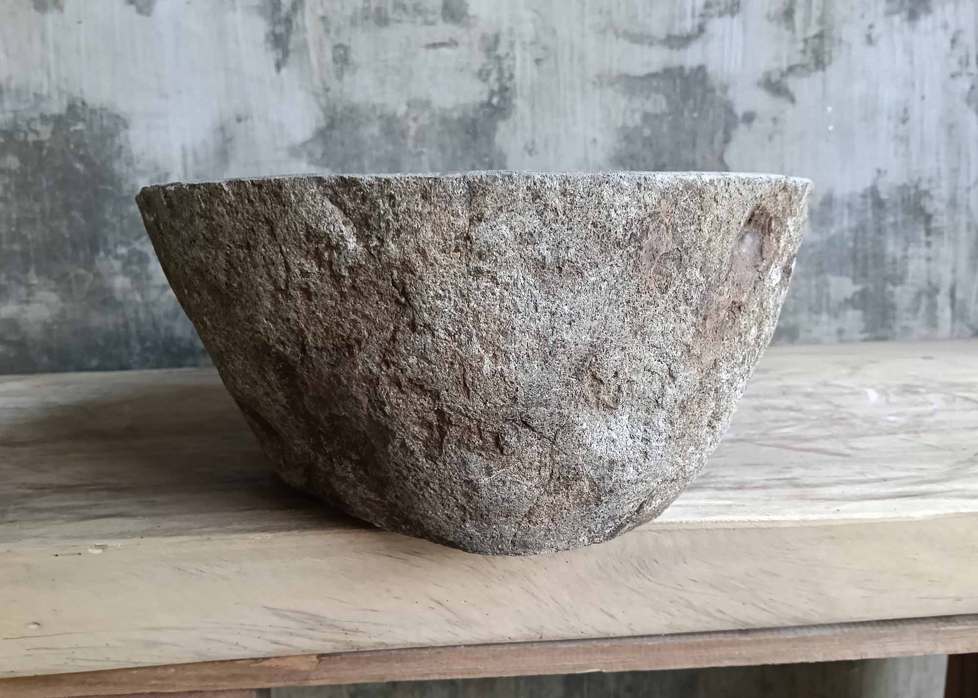 Left side of boat-profile sink in gray-brown natural stone
