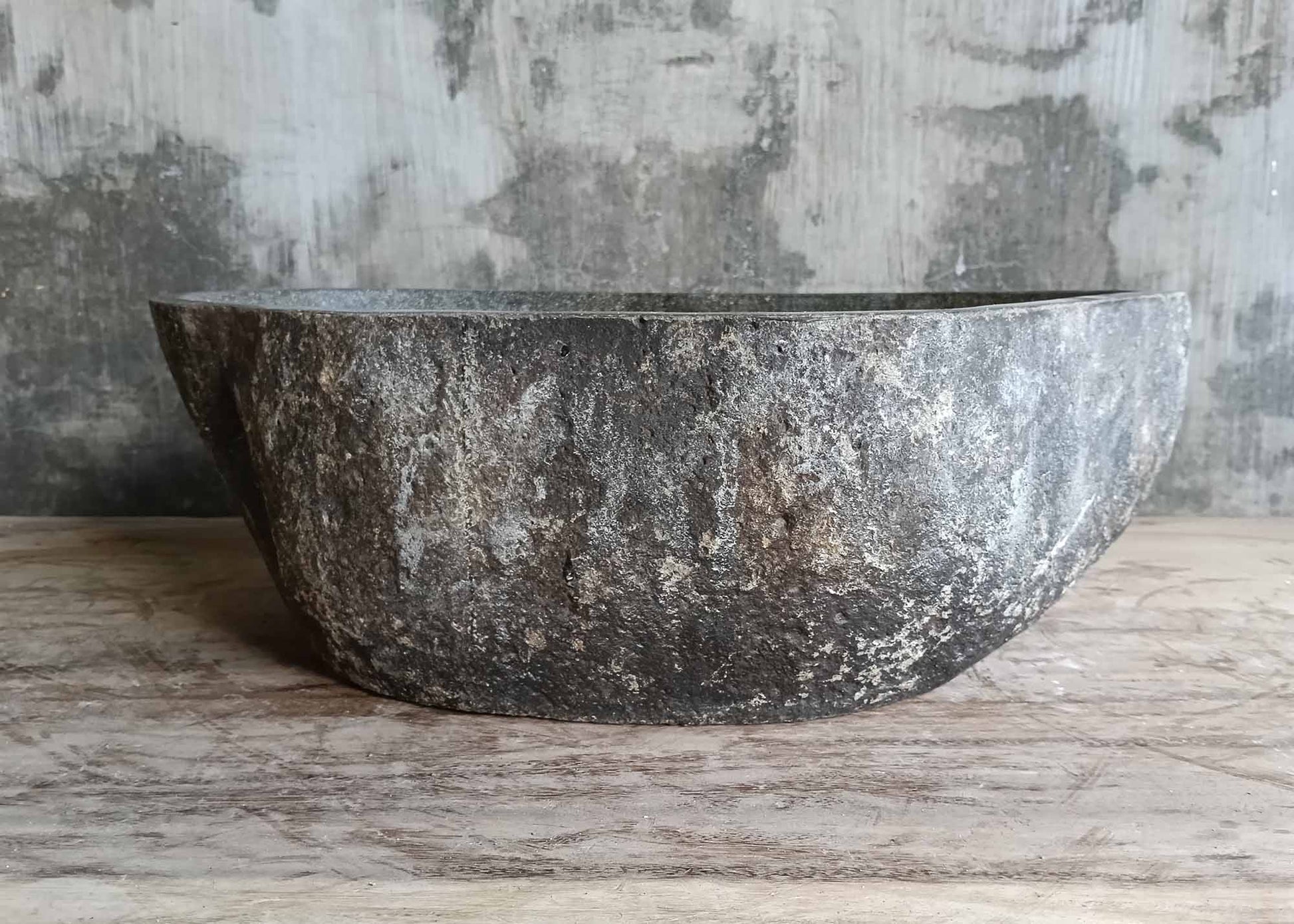 Rear side of elongated river stone basin in dark finish
