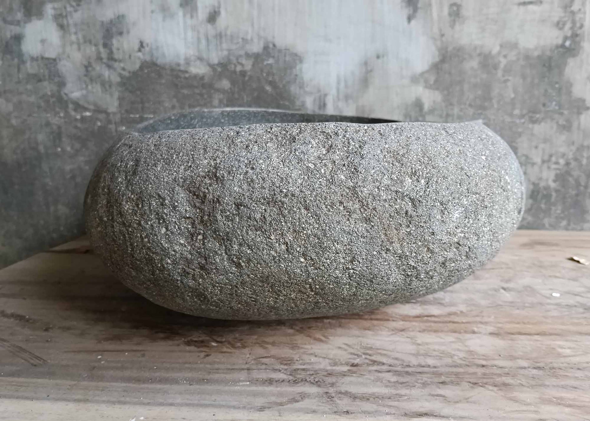 Left side of rounded handcrafted river stone sink in soft gray
