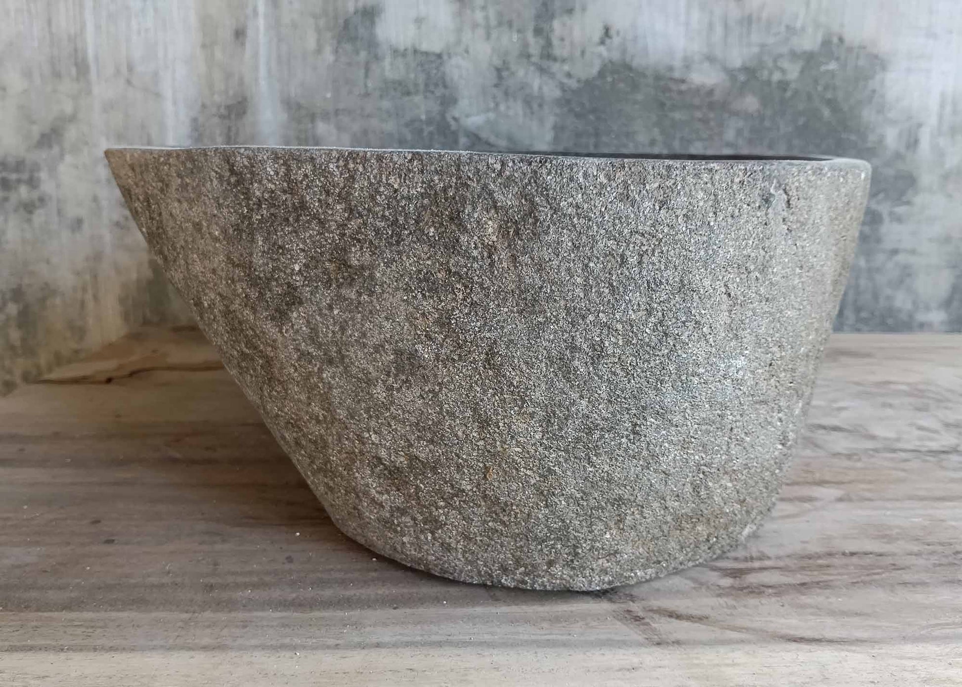 Back profile of round river stone sink in dark gray tones
