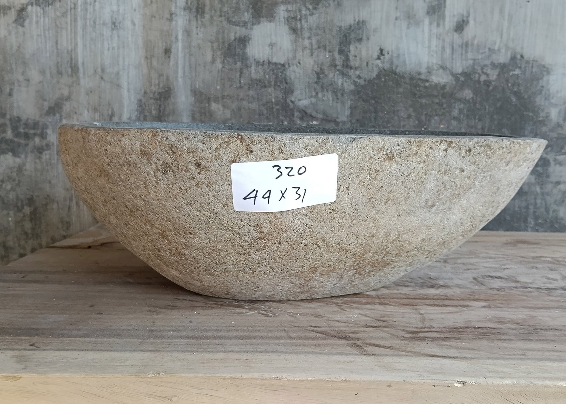 Front profile of river stone sink showing curved boat-like natural outer surface  

