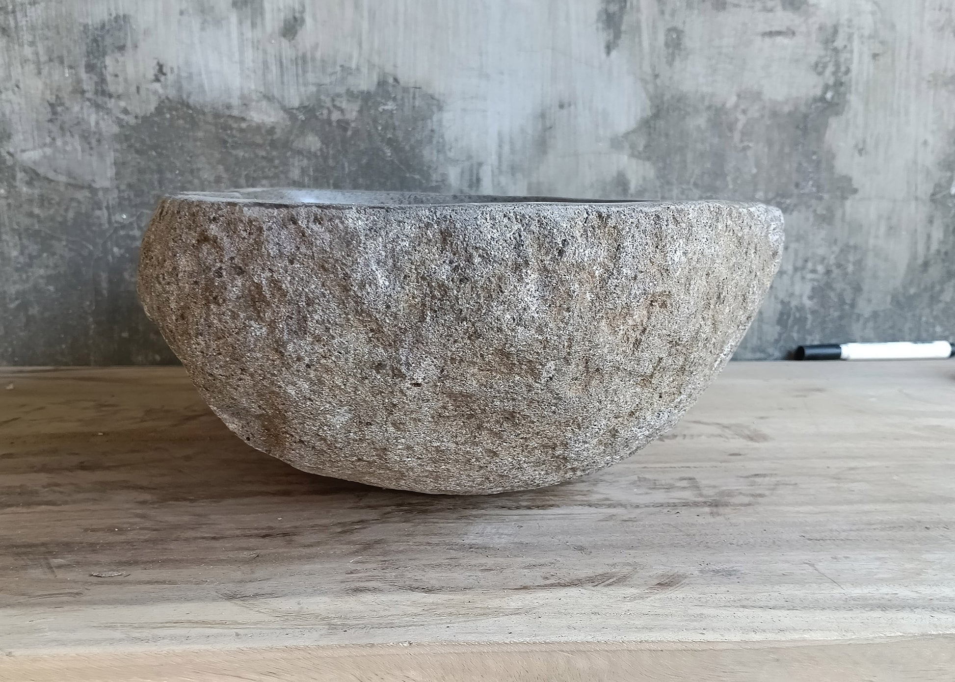Right side of boat-shaped handcrafted basin made from natural river stone  
