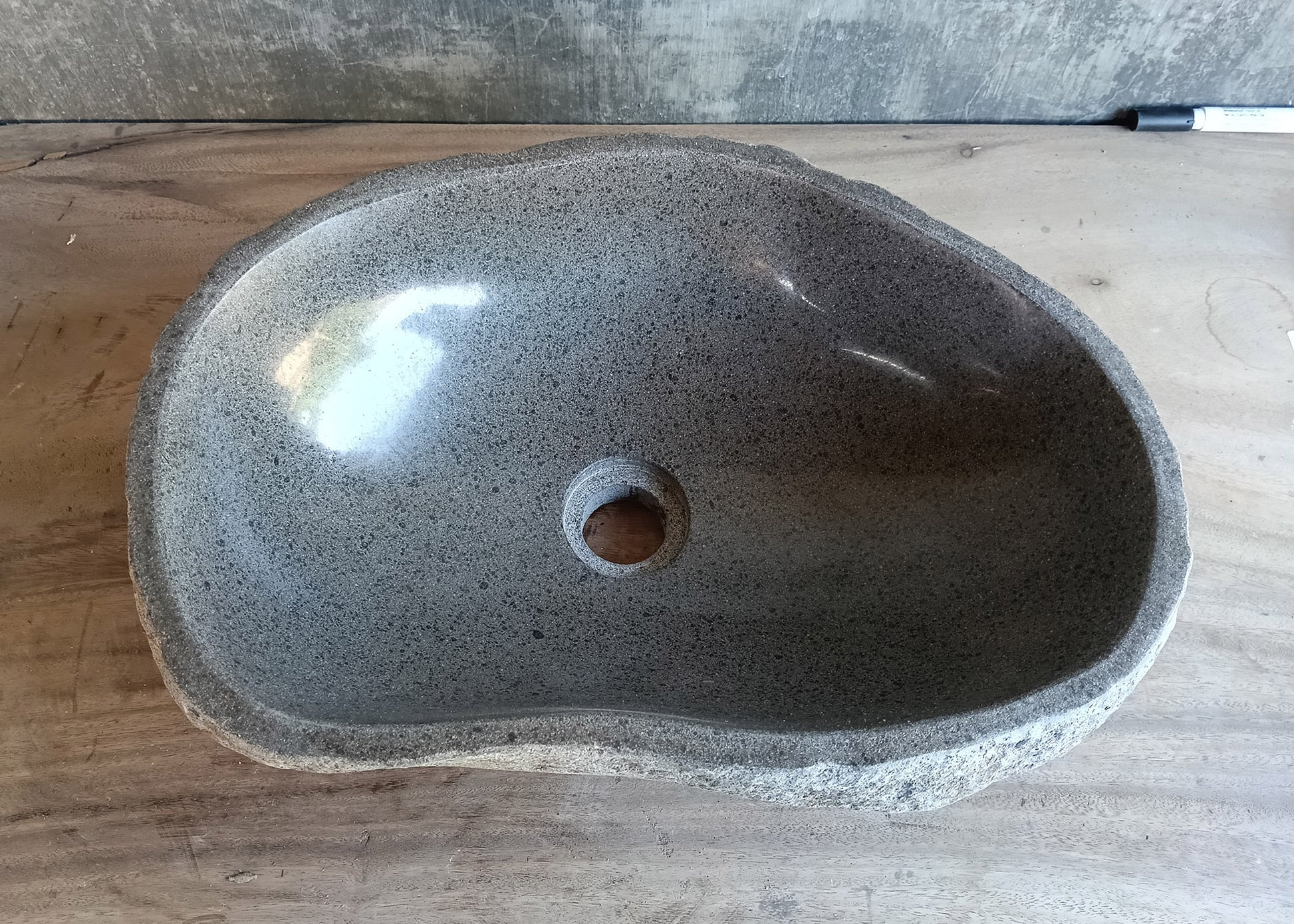 Top view of irregular gray river stone sink with polished interior and uneven rim  
