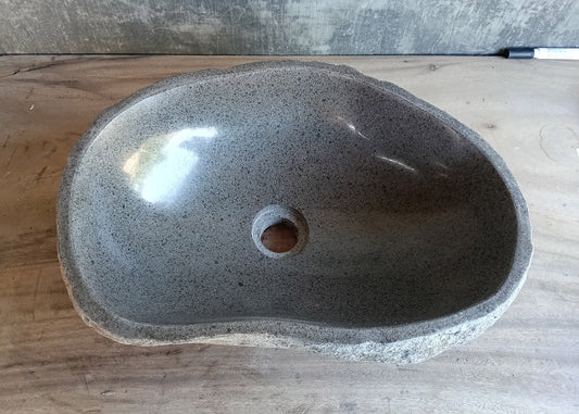 Top view of irregular gray river stone sink with polished interior and uneven rim  
